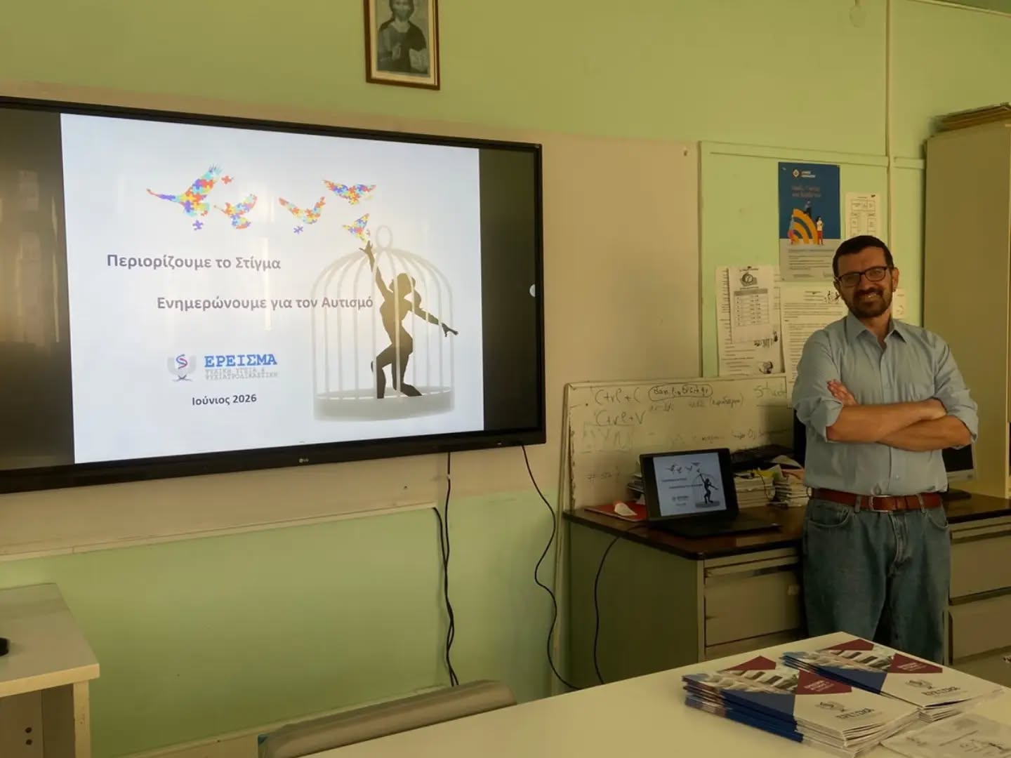Presenter in a classroom giving a talk about reducing stigma and autism awareness (June 2026) with a large screen showing butterflies and a cage image.